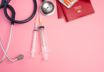 Directly above shot of medicines and passports on pink background