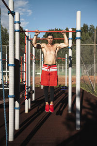 Athlete hanging on horizontal bars practicing at park