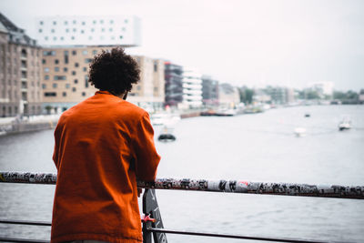 Rear view of man standing on river in city