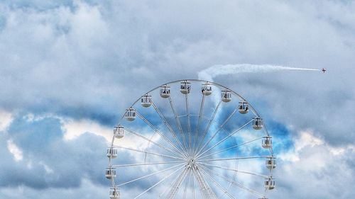 Low angle view of ferris wheel against cloudy sky