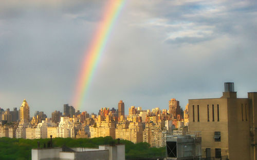 Rainbow over buildings in city against sky