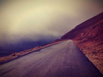 Road leading towards mountain against sky