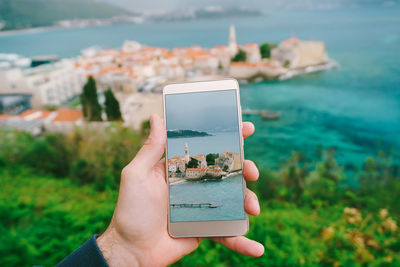 Close-up of hand holding mobile phone in sea