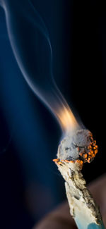 Close-up of burning cigarette against black background