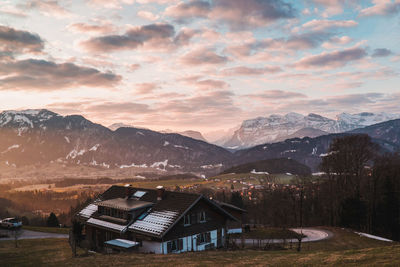 Houses by mountains against sky during sunset