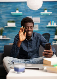 Young man using mobile phone while sitting on table