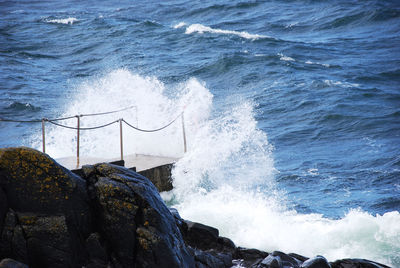 Waves splashing on shore against sky