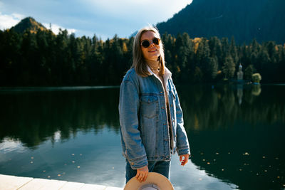 Young woman wearing sunglasses standing by lake