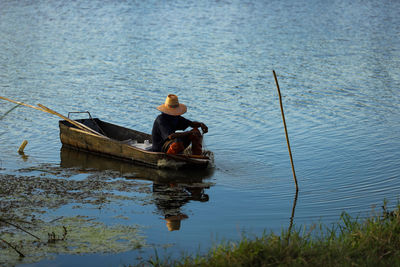 Rear view of man sitting on boat in lake