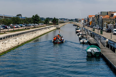 People on boat in river against sky in city