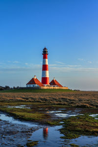 Lighthouse by sea against clear sky