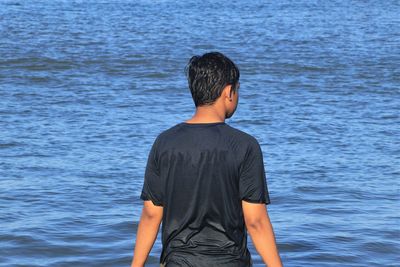 Rear view of man standing in sea