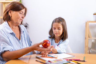 Portrait of smiling friends holding apple at home