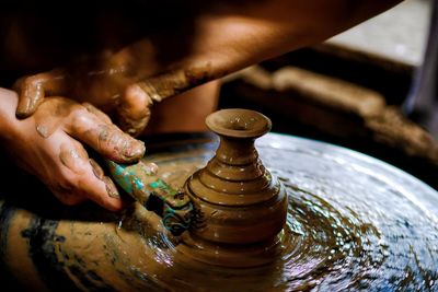 Cropped hands of person working on pottery wheel