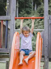 Full length of boy enjoying on slide at playground