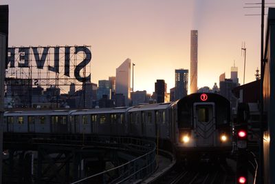 Railroad tracks in city against sky during sunset