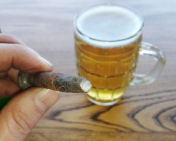 Close-up of hand holding beer glass on table