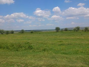 Scenic view of grassy field against cloudy sky