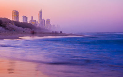 Scenic view of sea and buildings against sky during sunset