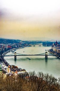 Bridge over river in city against sky