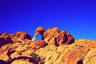 Low angle view of desert against clear blue sky