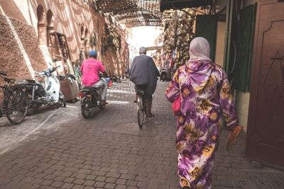 Rear view of people walking on street in city