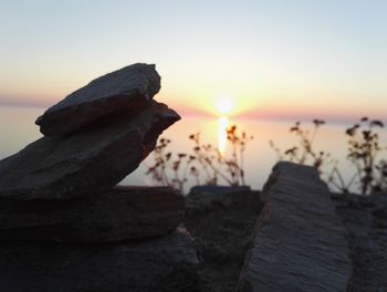 Close-up of rocks on shore against sky during sunset