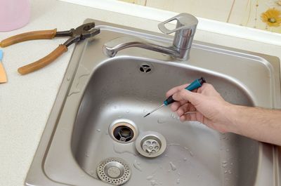 High angle view of hand holding screwdriver over sink