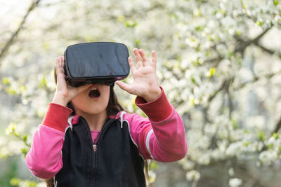 Surprise girl wearing virtual reality headset in park