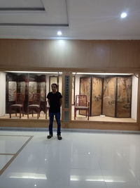 Full length portrait of man standing in illuminated store