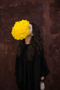 Young woman standing by yellow flower