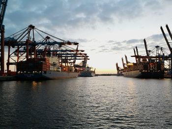 Cranes at commercial dock against sky