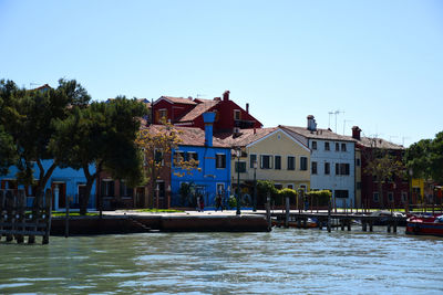 Houses by river and buildings against sky