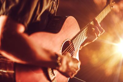 Midsection of man playing guitar