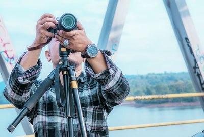 Man photographing through camera against sky