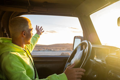 Man in car against sky seen through window