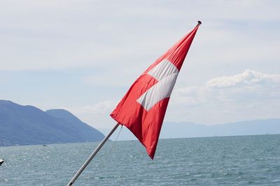 Red flag on sea against sky