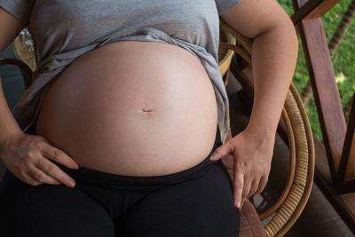 Midsection of pregnant woman resting on chair