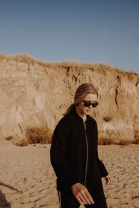 Young woman wearing sunglasses standing on ground