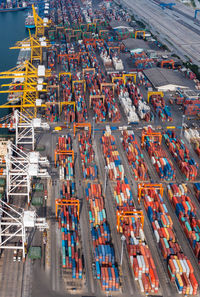 Warehouse stacking containers group in a row and cranes load unloading in shipping commercial port 