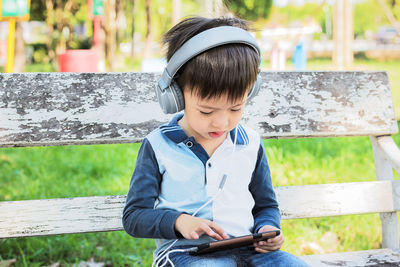 Full length of boy using mobile phone while sitting outdoors