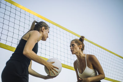 Low angle view of female friends playing volleyball near net