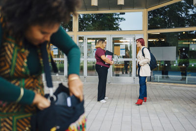 Female students talking with each other while standing at university campus