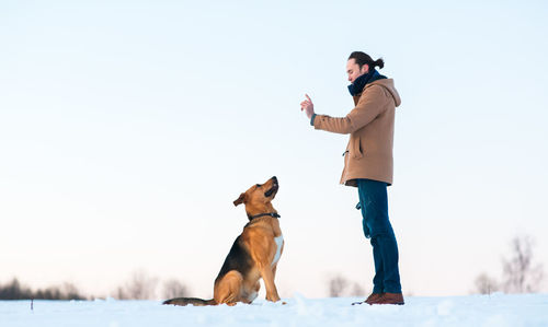 Man with dog on snow field during winter