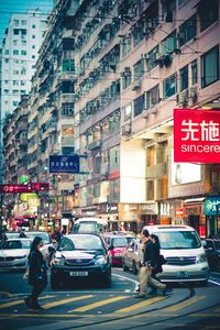 People and traffic on street amidst buildings in city