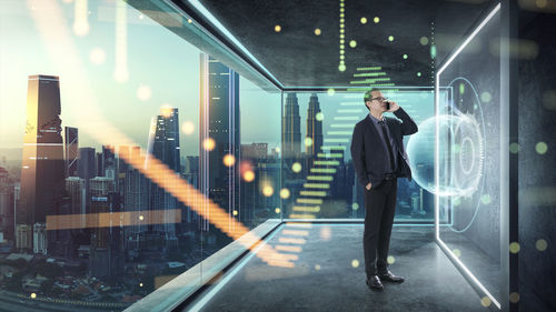 Digital composite image of businessman talking on smart phone while standing by icons in office