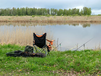 Beautiful lake landscape with a fishing chair and fishing accessories on the lake shore