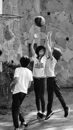 Siblings playing basketball on footpath