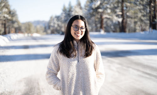 Portrait of smiling young woman standing in snow