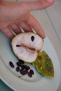 Close-up of hand holding fruit in plate